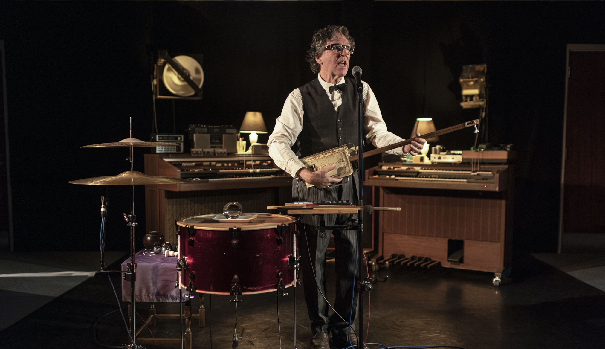 Singing musician on stage accompanies himself with one-string-tin-can-bass